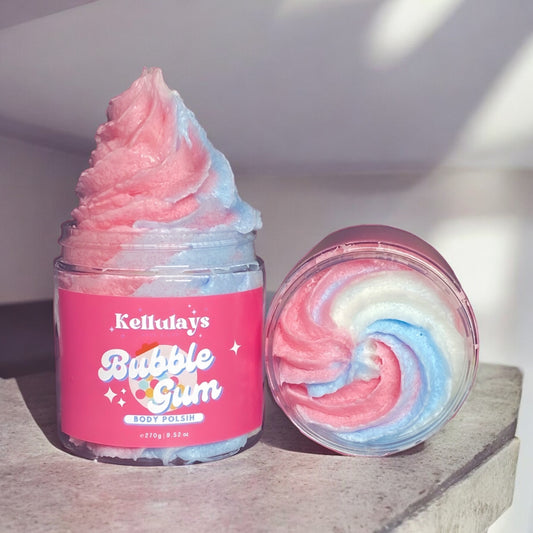 Image of Kellulays Bubblegum Body Polish displayed in a clear jar with a pink label. The product features a swirl of pink, blue, and white Colours resembling a soft serve ice cream texture. The label shows the Kellulays logo and product name in playful fonts. Next to the jar is a lid displaying the same swirl pattern from above, showcasing the vibrant colors and creamy texture of the body polish.