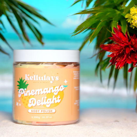 Kellulays Pinemango Delight Body Polish: A 290g jar of tropical body polish featuring a colorful label with a pineapple and mango graphic, set against a vibrant beach background with lush green palm leaves and vivid red flowers, evoking a sense of paradise and relaxation.