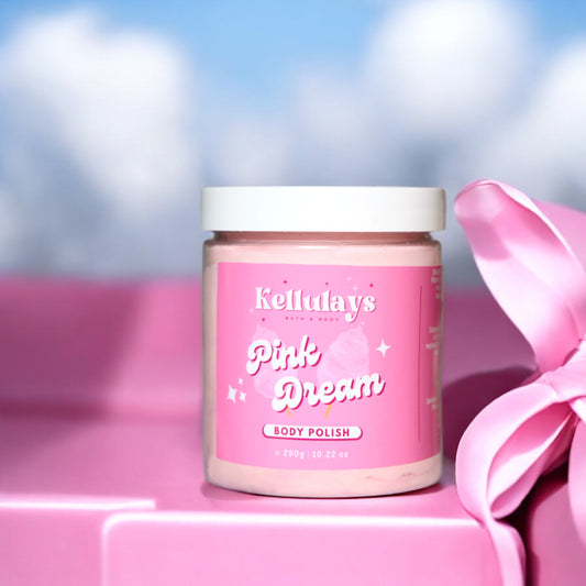 Jar of Kellulays ‘Pink Dream’ body polish with a pink label, set against a backdrop of soft clouds and pink gift boxes with ribbons, conveying a dreamy and whimsical atmosphere.