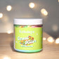 Jar of Kellulays ‘Cereal Killer’ body polish with a green label featuring a colorful cereal bowl image, set against a blurred background with glowing lights.