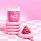 Jar of Kellulays Lychee Peony Body Polish on a pink and white checkered surface, with a pink whipped swirl next to it, creating a vibrant and stylish presentation.