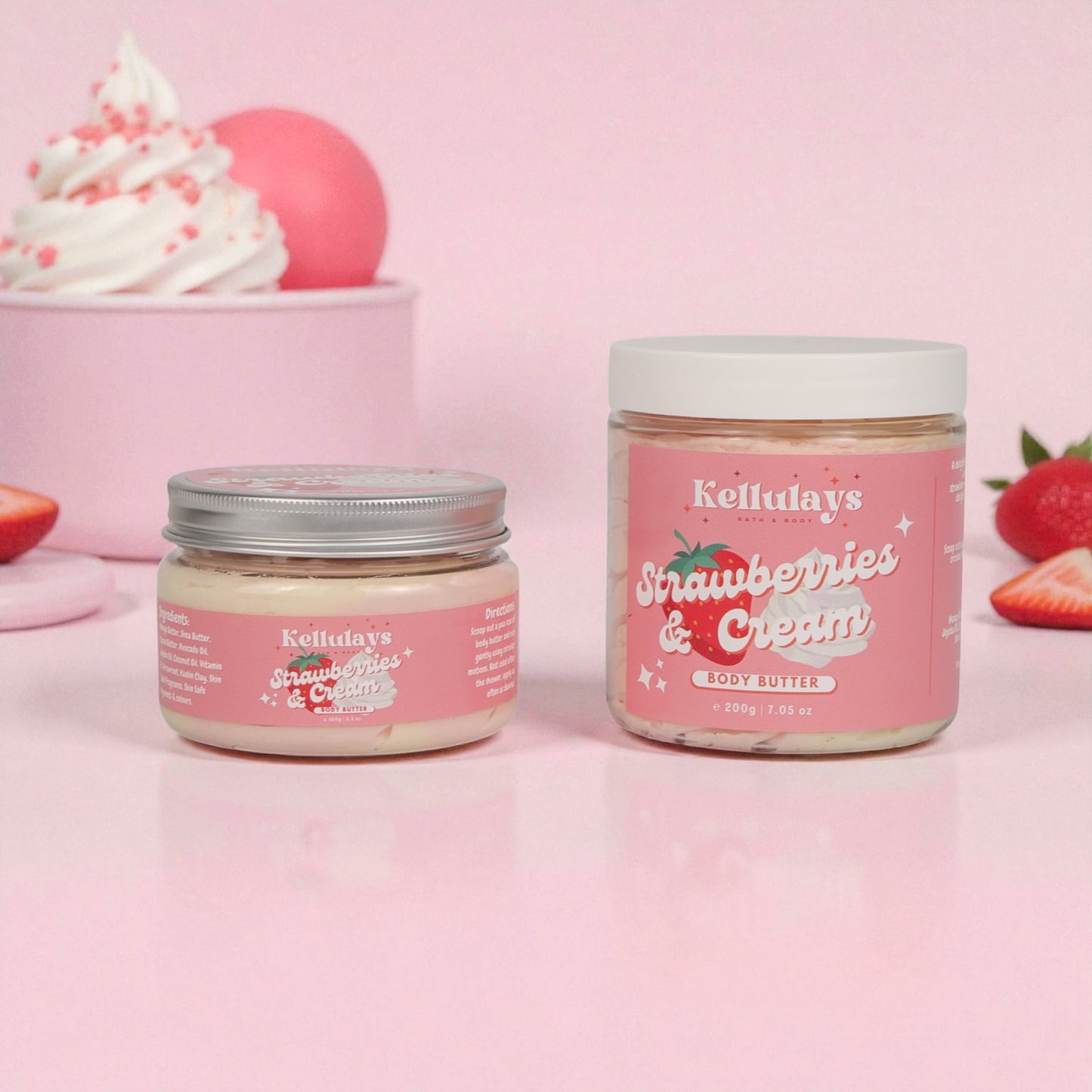 Two jars of Kellulay's Strawberries & Cream body butter on a pink background with strawberries and whipped cream.