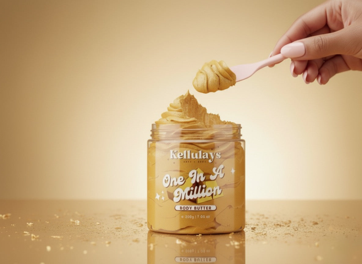 A close up shot of a jar of Kellulays One In A Million body butter with gold whipped swirl texture, as a hand with soft pink nails scoops the product using a pink spatula. The scene is set against a warm golden background with scattered golden crumbs, giving it a luxurious, perfume inspired aesthetic.