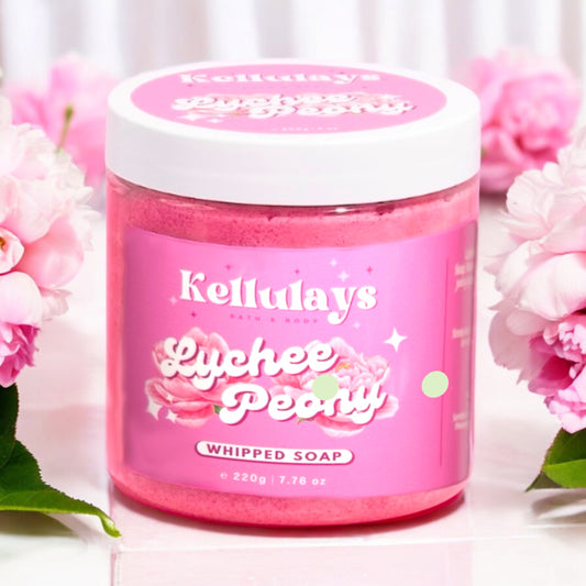 Pink jar of Kellulays Lychee Peony Whipped Soap with a white lid, featuring an elegant label design displaying the product name and floral motifs. The jar is surrounded by pink peony flowers, enhancing the soap's luxurious and vibrant aesthetic.